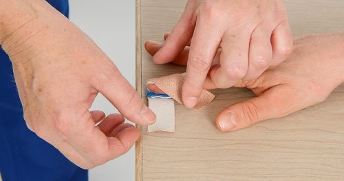 Påfør dernæst skinnen ved at løfte op i fingeren.   På skinnen påføres let-elastisk plaster, hvorefter plasterets ender krydser hinanden oven på fingerens yderste led. 