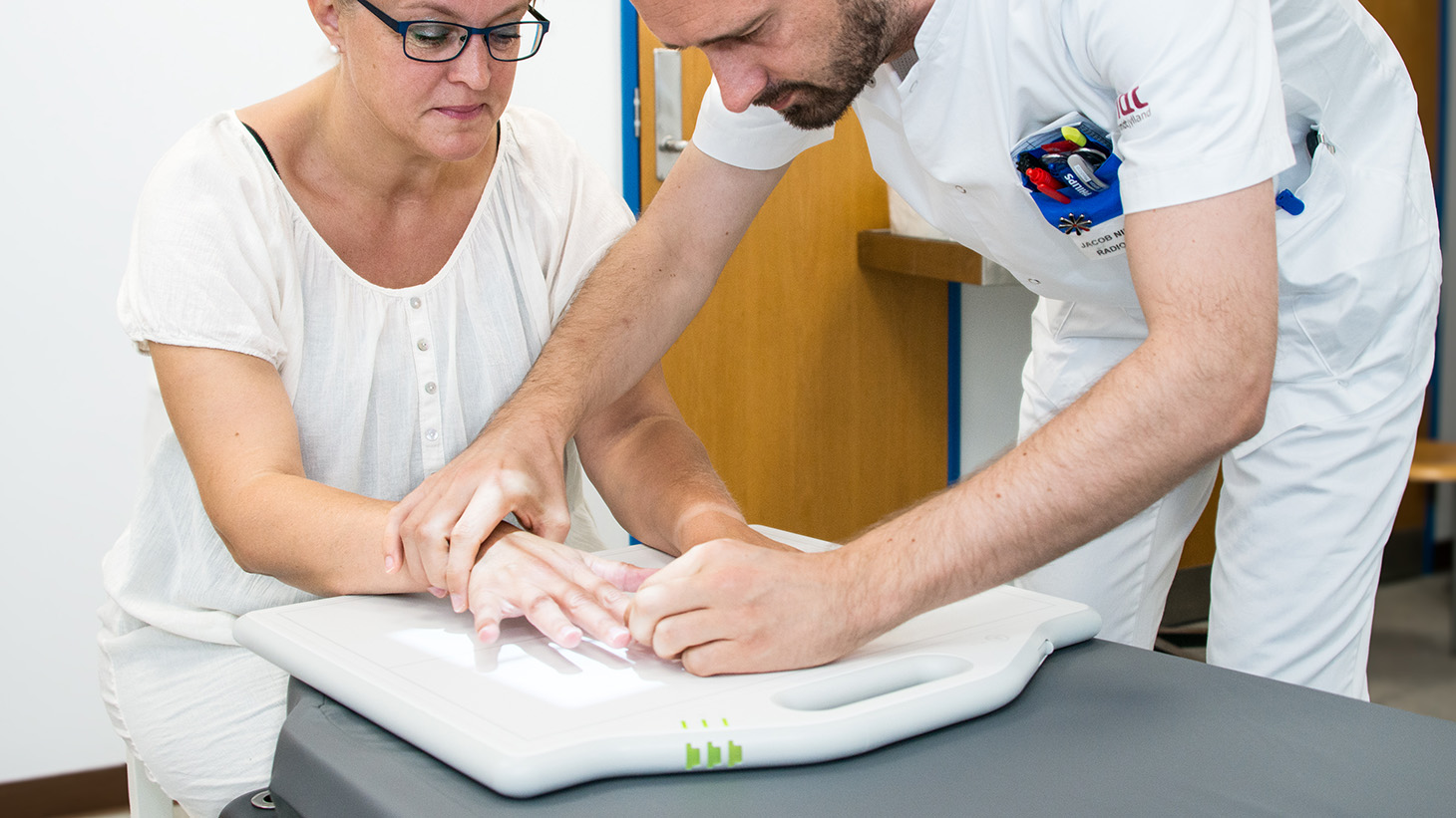 Medarbejder justerer kvindes hånd for at kunne tage et røntgenbillede